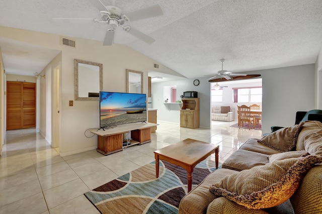 tiled living room featuring a textured ceiling, ceiling fan, and vaulted ceiling