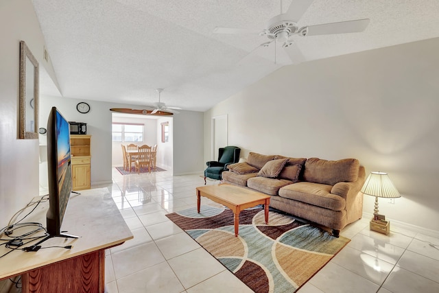 living room featuring lofted ceiling, a textured ceiling, light tile patterned flooring, and ceiling fan