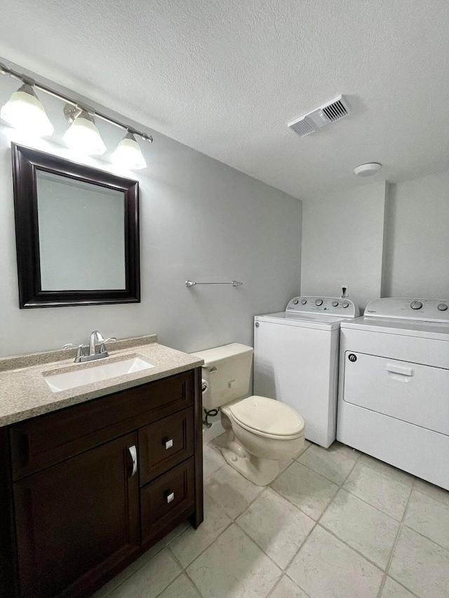 bathroom featuring separate washer and dryer, vanity, a textured ceiling, toilet, and tile patterned floors