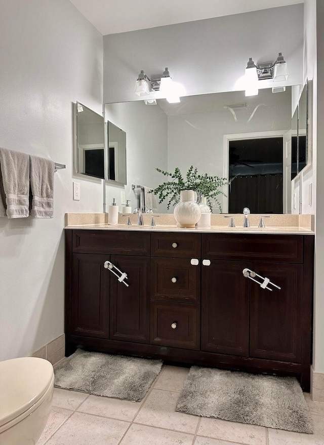 bathroom with a sink, toilet, and double vanity