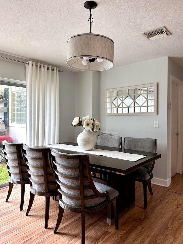 dining room with a textured ceiling and wood-type flooring