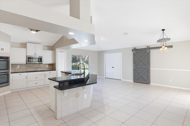 kitchen featuring stainless steel appliances, white cabinets, sink, and a barn door