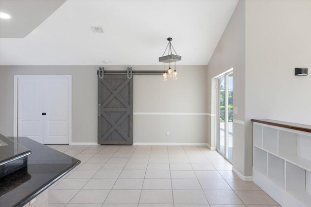 unfurnished dining area featuring light tile patterned floors, lofted ceiling, and a barn door