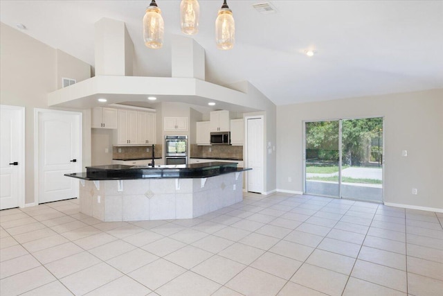 kitchen featuring white cabinets, light tile patterned floors, decorative light fixtures, high vaulted ceiling, and appliances with stainless steel finishes