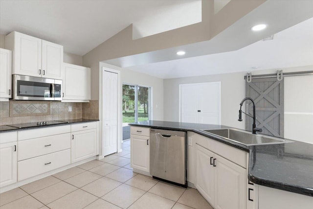 kitchen with white cabinetry, tasteful backsplash, a barn door, stainless steel appliances, and sink