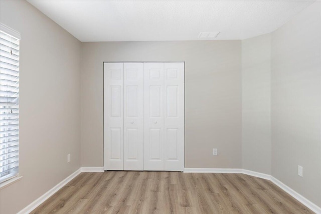 unfurnished bedroom featuring light wood-type flooring and a closet