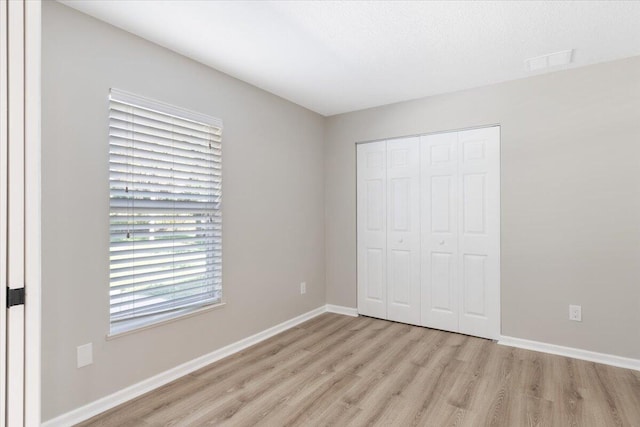 unfurnished bedroom with light wood-type flooring, a closet, and a textured ceiling