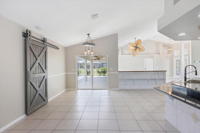 kitchen featuring a barn door, light tile patterned floors, vaulted ceiling, and pendant lighting