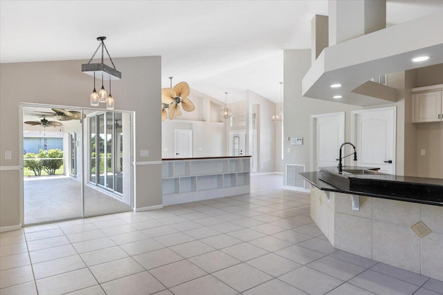 kitchen with light tile patterned floors, sink, high vaulted ceiling, and decorative light fixtures