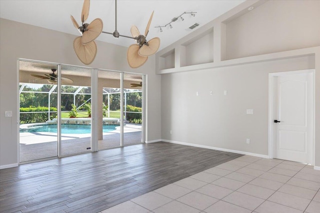 empty room featuring ceiling fan, light wood-type flooring, and high vaulted ceiling