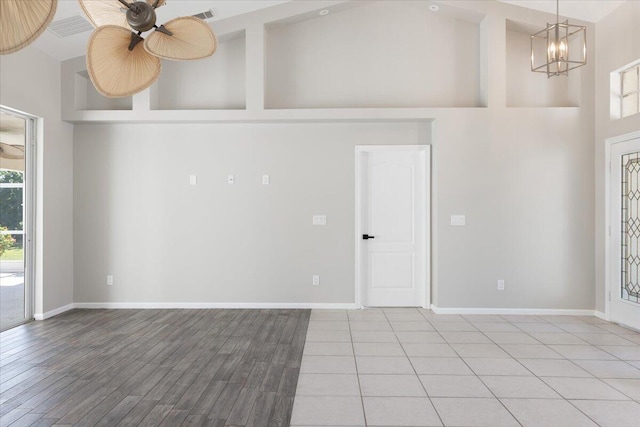 empty room with high vaulted ceiling, light hardwood / wood-style floors, beamed ceiling, and ceiling fan with notable chandelier