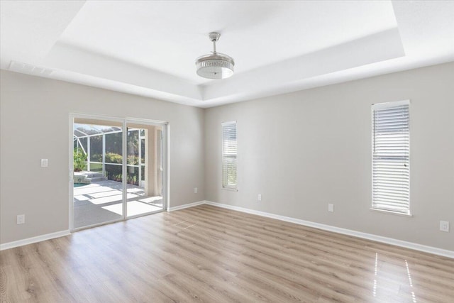 empty room featuring a tray ceiling and light hardwood / wood-style flooring