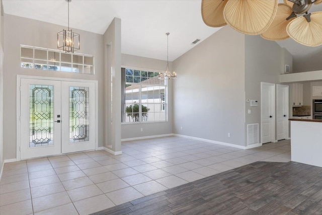 entryway featuring light tile patterned floors, french doors, and high vaulted ceiling