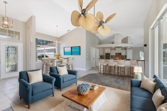 tiled living room with ceiling fan and high vaulted ceiling