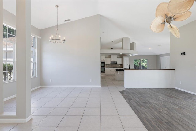 interior space with ceiling fan with notable chandelier, sink, light hardwood / wood-style flooring, and high vaulted ceiling