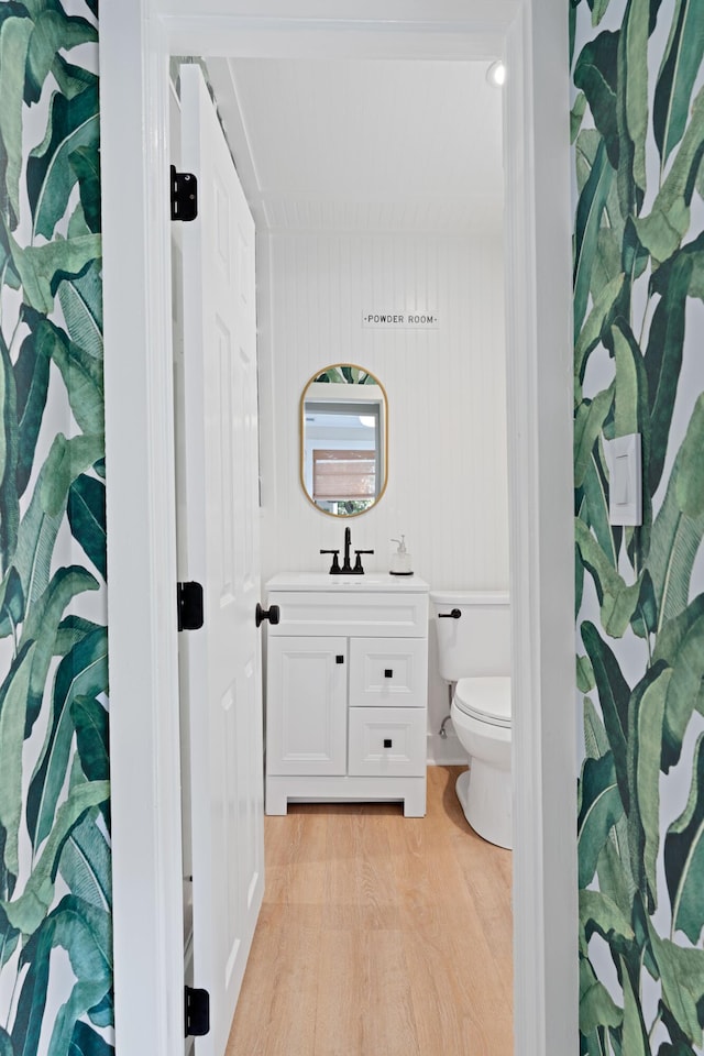 bathroom with vanity, hardwood / wood-style floors, toilet, and wood walls