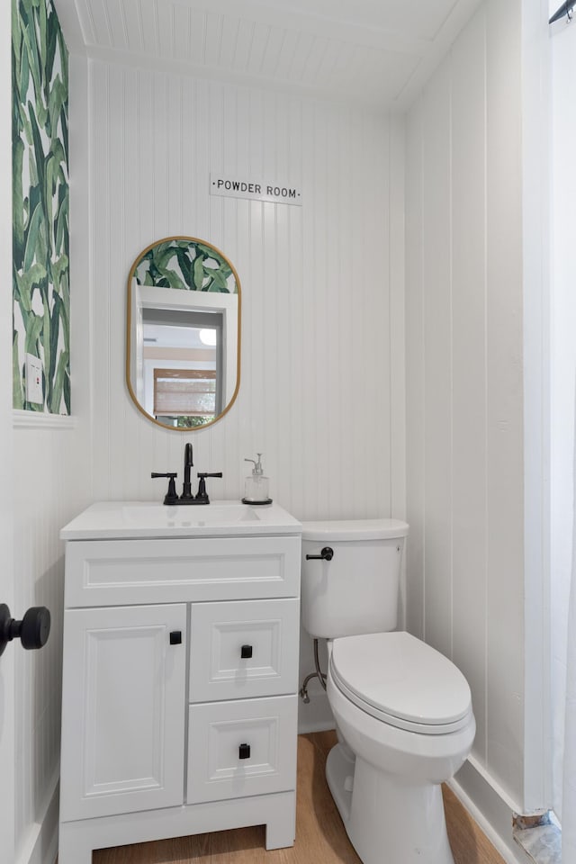 bathroom with vanity, toilet, and wooden walls