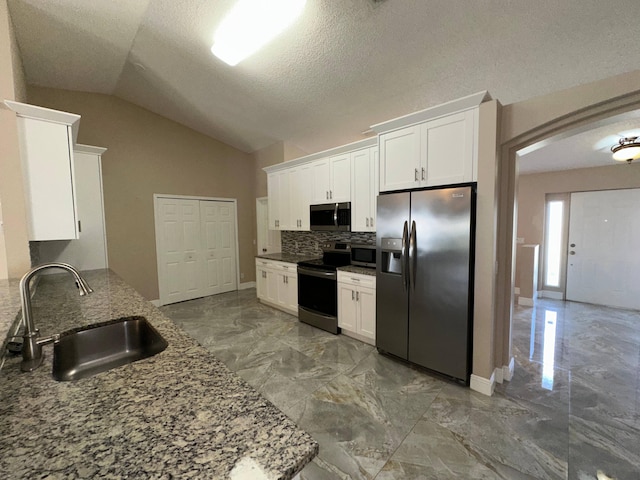 kitchen featuring stainless steel appliances, sink, lofted ceiling, and white cabinetry