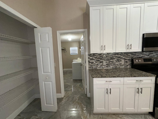 kitchen featuring dark stone countertops, white cabinetry, tasteful backsplash, and range