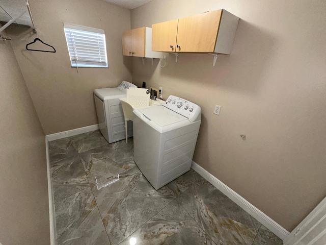 clothes washing area featuring cabinets and separate washer and dryer