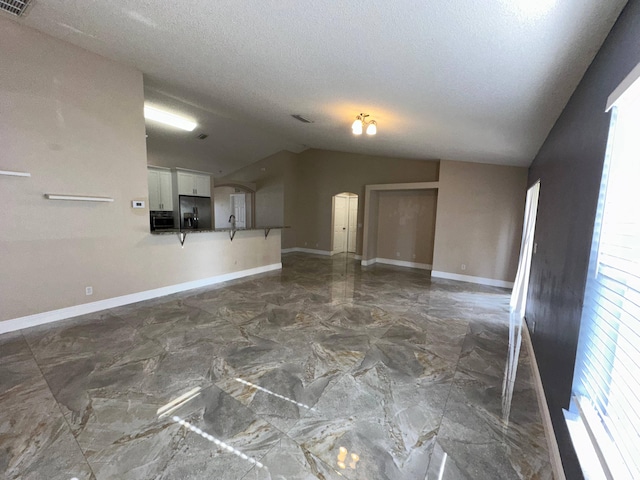 empty room featuring a textured ceiling and lofted ceiling