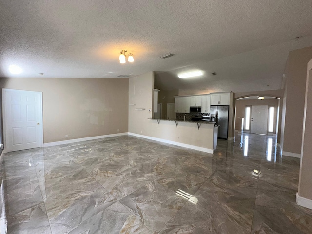 unfurnished living room featuring a textured ceiling and lofted ceiling