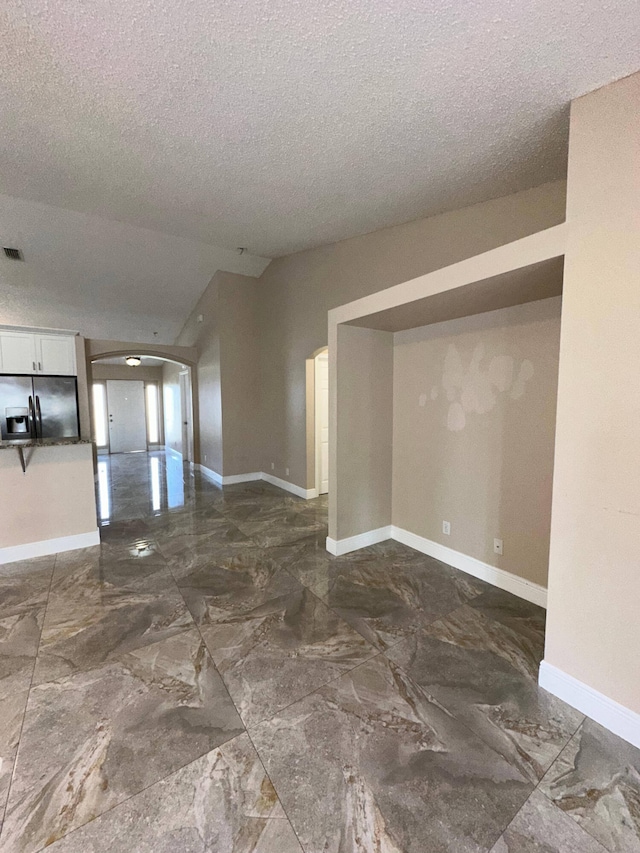 empty room featuring a textured ceiling and lofted ceiling