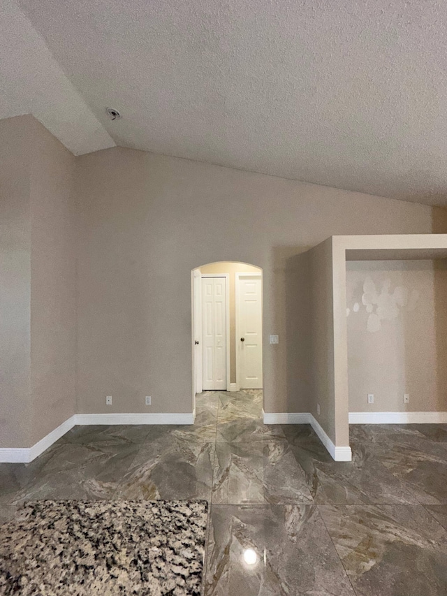 spare room with a textured ceiling and vaulted ceiling