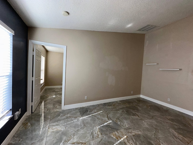 unfurnished room featuring vaulted ceiling, a textured ceiling, and a healthy amount of sunlight