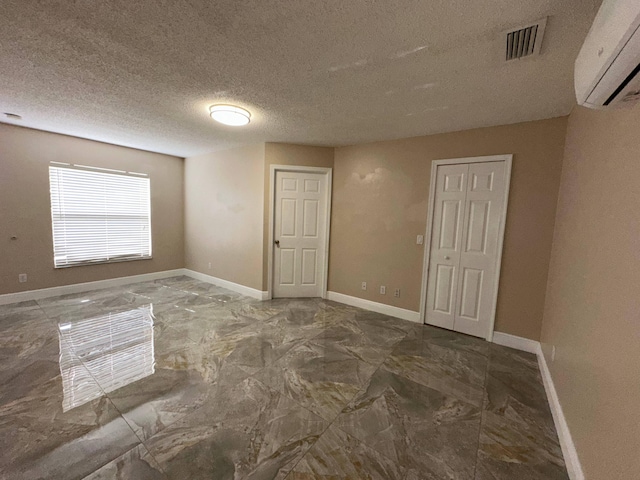 spare room with an AC wall unit and a textured ceiling