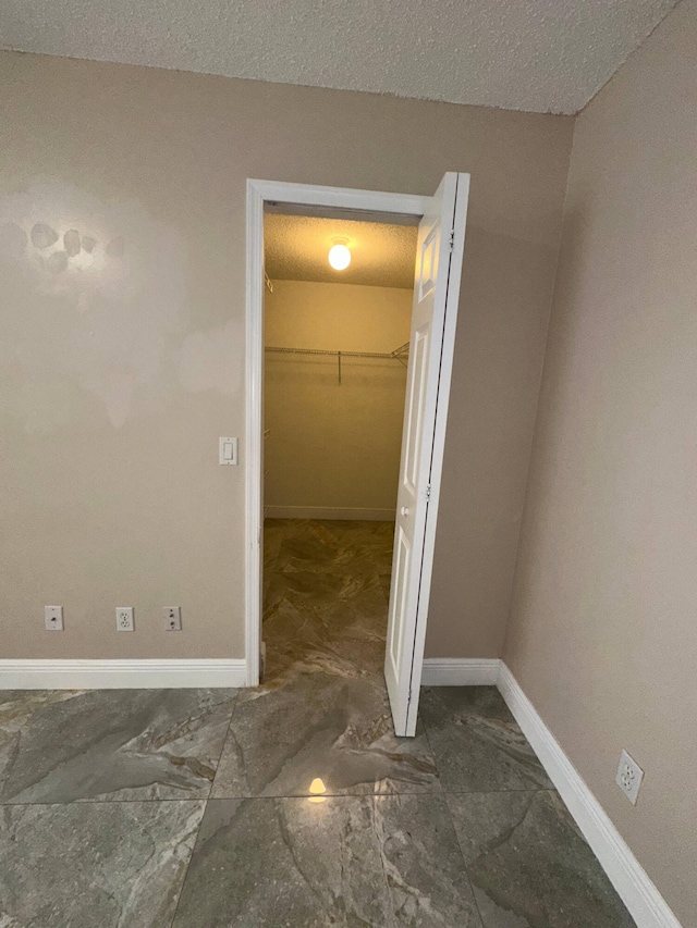 interior space with a textured ceiling, a walk in closet, and a closet