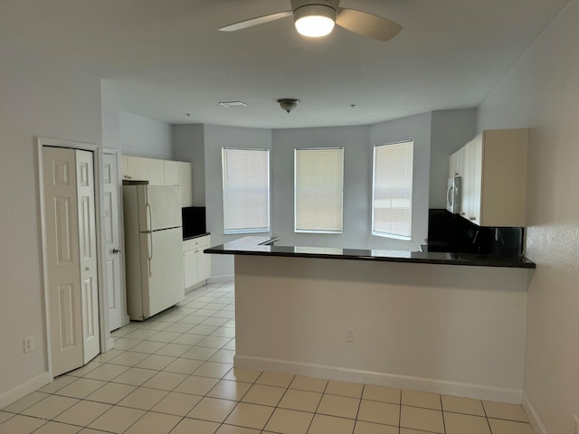 kitchen featuring light tile patterned floors, kitchen peninsula, white appliances, and white cabinetry