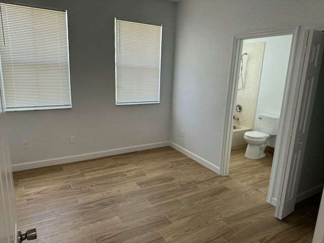 unfurnished bedroom with light wood-type flooring and ensuite bathroom