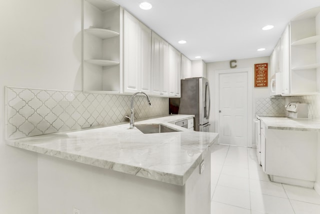 kitchen with open shelves, a sink, white microwave, light stone countertops, and stove