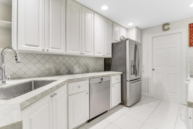 kitchen featuring tasteful backsplash, a sink, light tile patterned floors, stainless steel appliances, and white cabinets