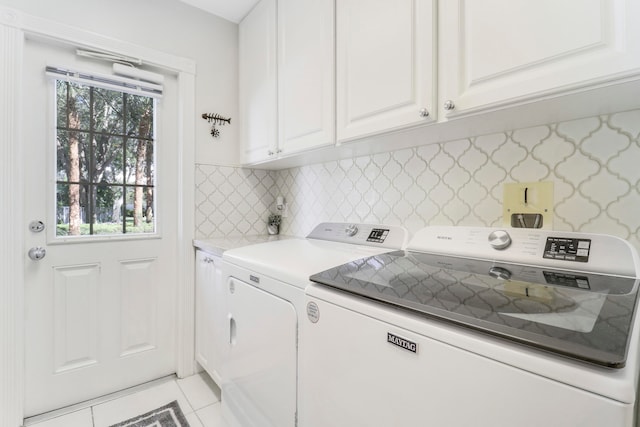 clothes washing area with cabinets, light tile patterned floors, and washing machine and dryer