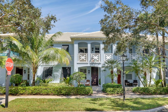 view of front of home with a balcony and a front lawn