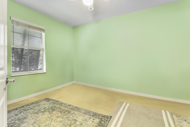 empty room with a ceiling fan and baseboards
