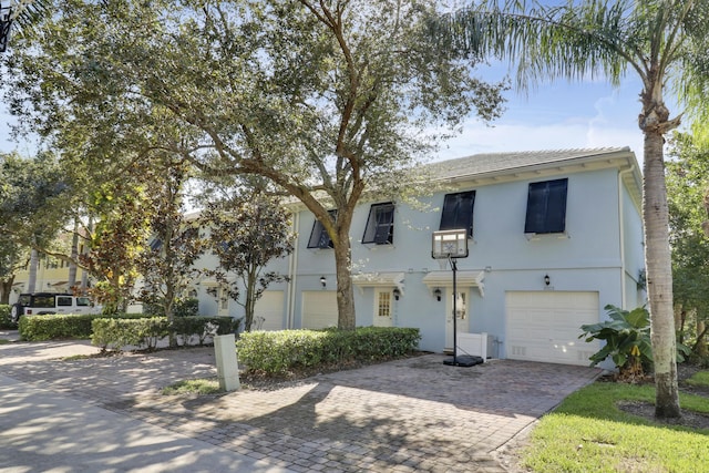 view of property with stucco siding, decorative driveway, and a garage
