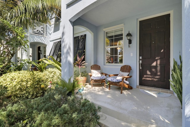entrance to property with covered porch and stucco siding