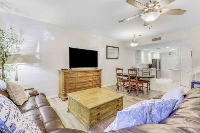 living area with baseboards, light wood-style flooring, visible vents, and a ceiling fan