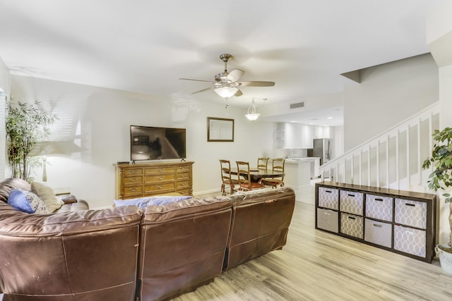 living area with stairway, ceiling fan, wood finished floors, and visible vents