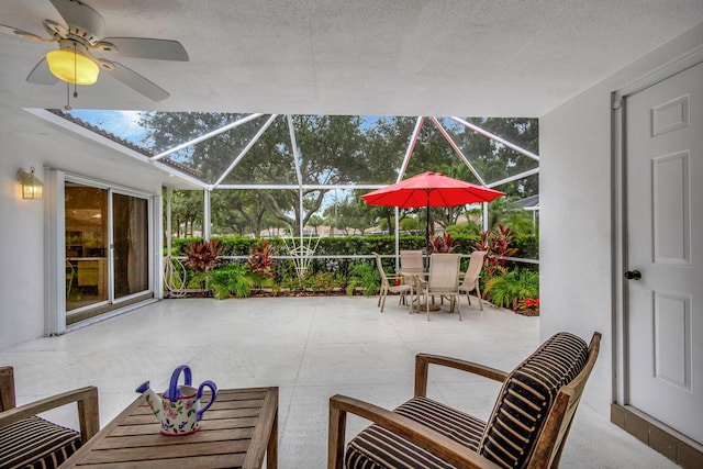 view of patio featuring ceiling fan and glass enclosure