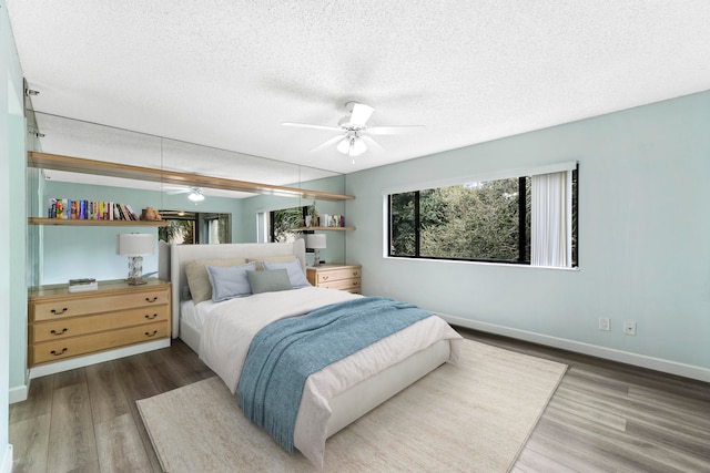 bedroom with hardwood / wood-style floors, ceiling fan, and a textured ceiling