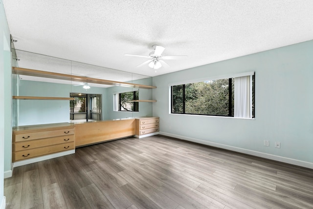 unfurnished bedroom with wood-type flooring, a textured ceiling, and ceiling fan