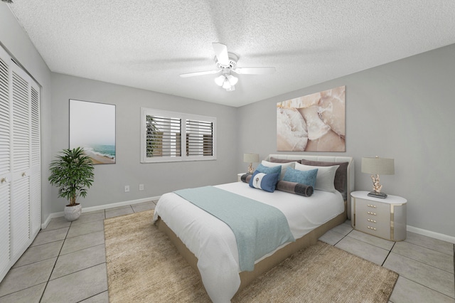 bedroom with a closet, light tile patterned flooring, ceiling fan, and a textured ceiling