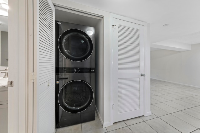 laundry area with light tile patterned flooring and stacked washer / dryer