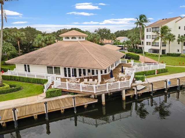 back of house with a deck with water view and a lawn