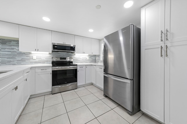 kitchen with white cabinets, light tile patterned floors, appliances with stainless steel finishes, and tasteful backsplash