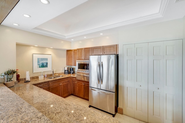 kitchen with stainless steel appliances, kitchen peninsula, sink, a raised ceiling, and light stone countertops